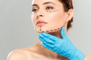 plastic surgeon touching face of attractive woman with marked face