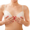 Woman in white bra covering her small breast with her hands