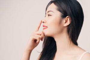 beautiful Asian woman with smiley face and red lips touching her nose
