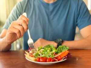 A close-up shot of a man eating a salad.