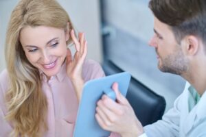 Doctor showing woman her new ears in a mirror after full recovery from otoplasty