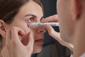 A plastic surgeon is preparing for a blepharoplasty operation to enhance the appearance of the eyelids and rejuvenate the eye area.