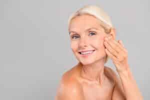 Happy woman applying daily anti-wrinkle cream on face, promoting fresh skin, beauty, and healthy skincare routine.