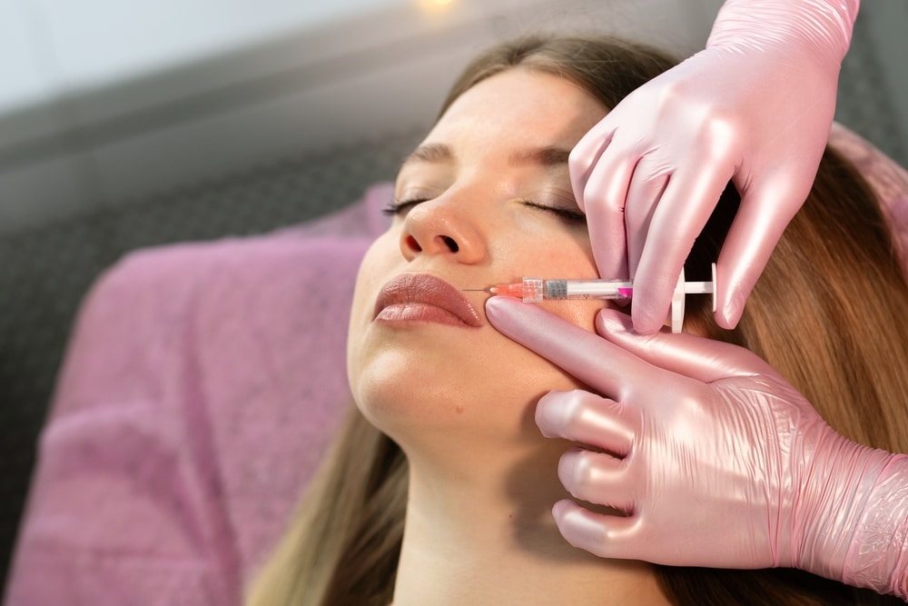 Doctor drawing pre-surgery markings on woman’s abdomen with marker before tummy tuck abdominoplasty procedure